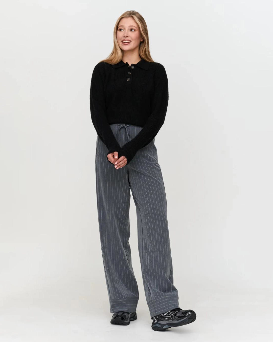 a woman wears a black ribbed knit polo sweater