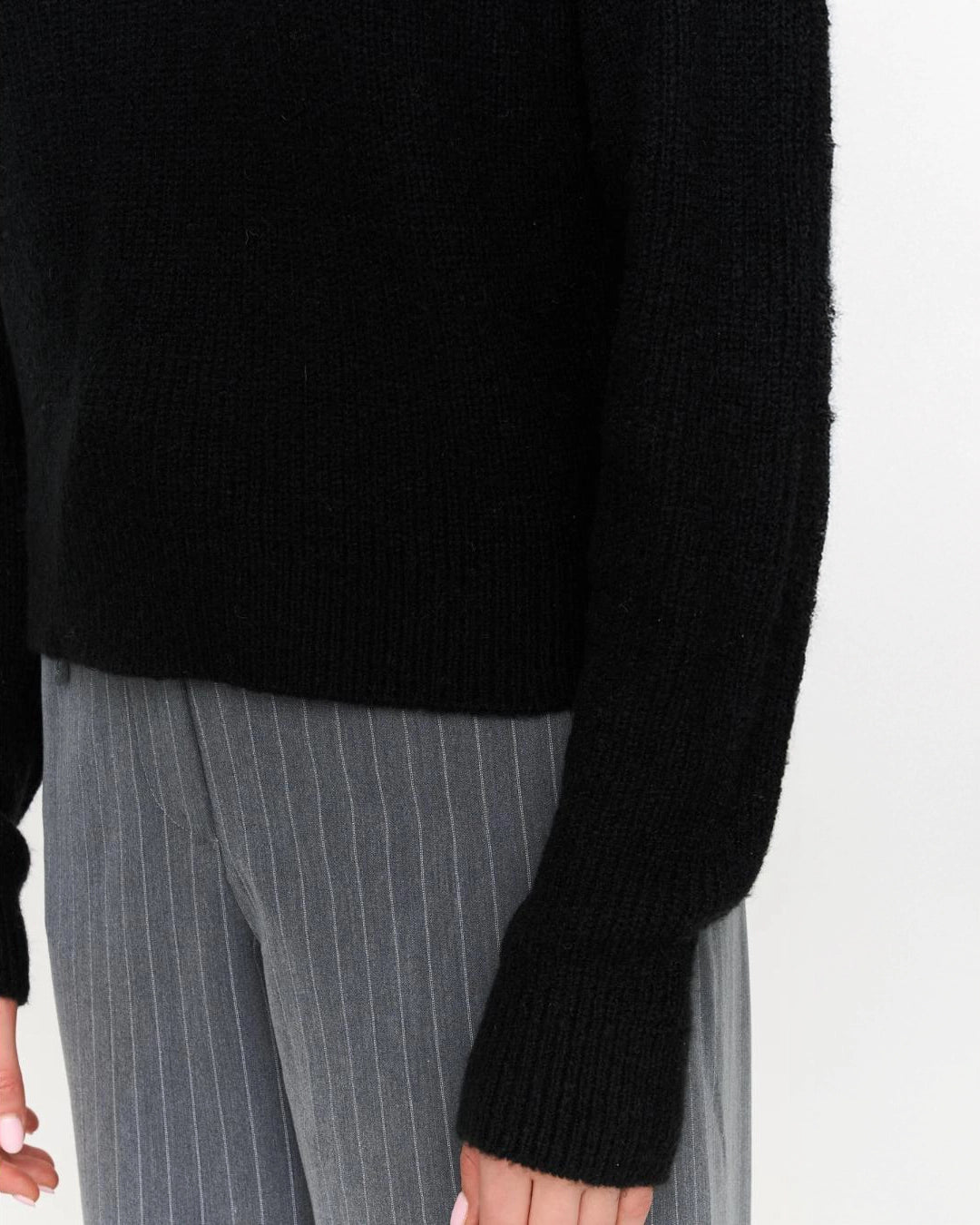 a woman wears a black ribbed knit sweater