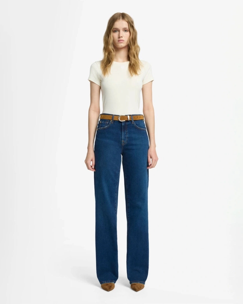 A woman wearing blue mid rise jeans by 7 For All Mankind