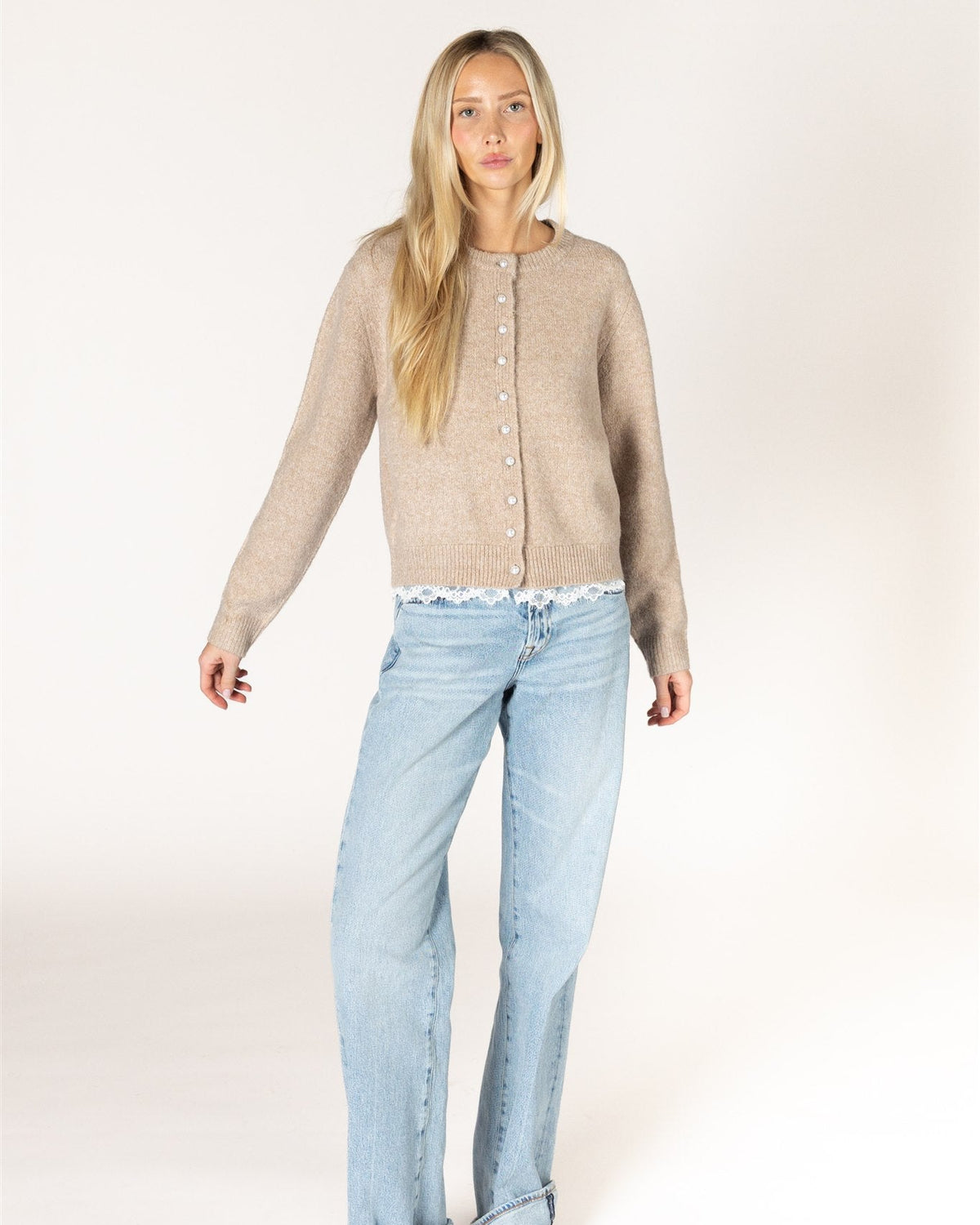 beige knit cardigan with pearl buttons and lace trim on the bottom