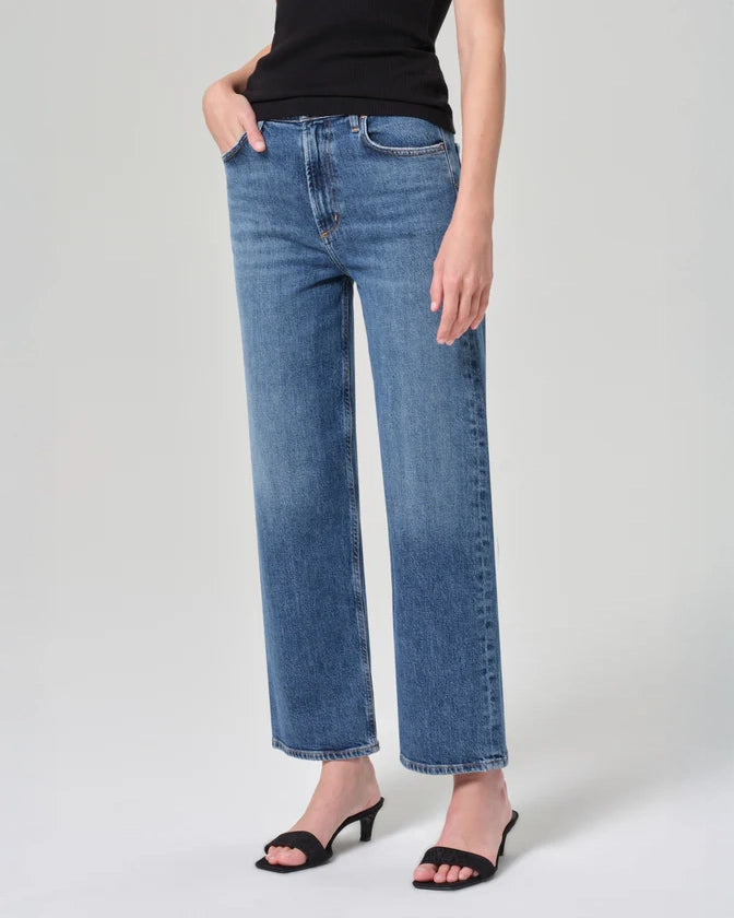 Person wearing mid rise blue jeans in medium wash