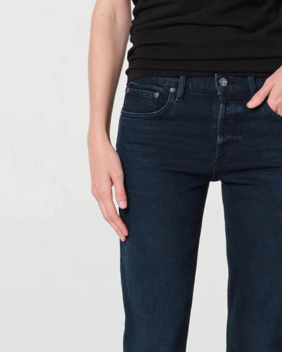 a woman wears a pair of skinny ankle cut dark denim jeans by Agolde