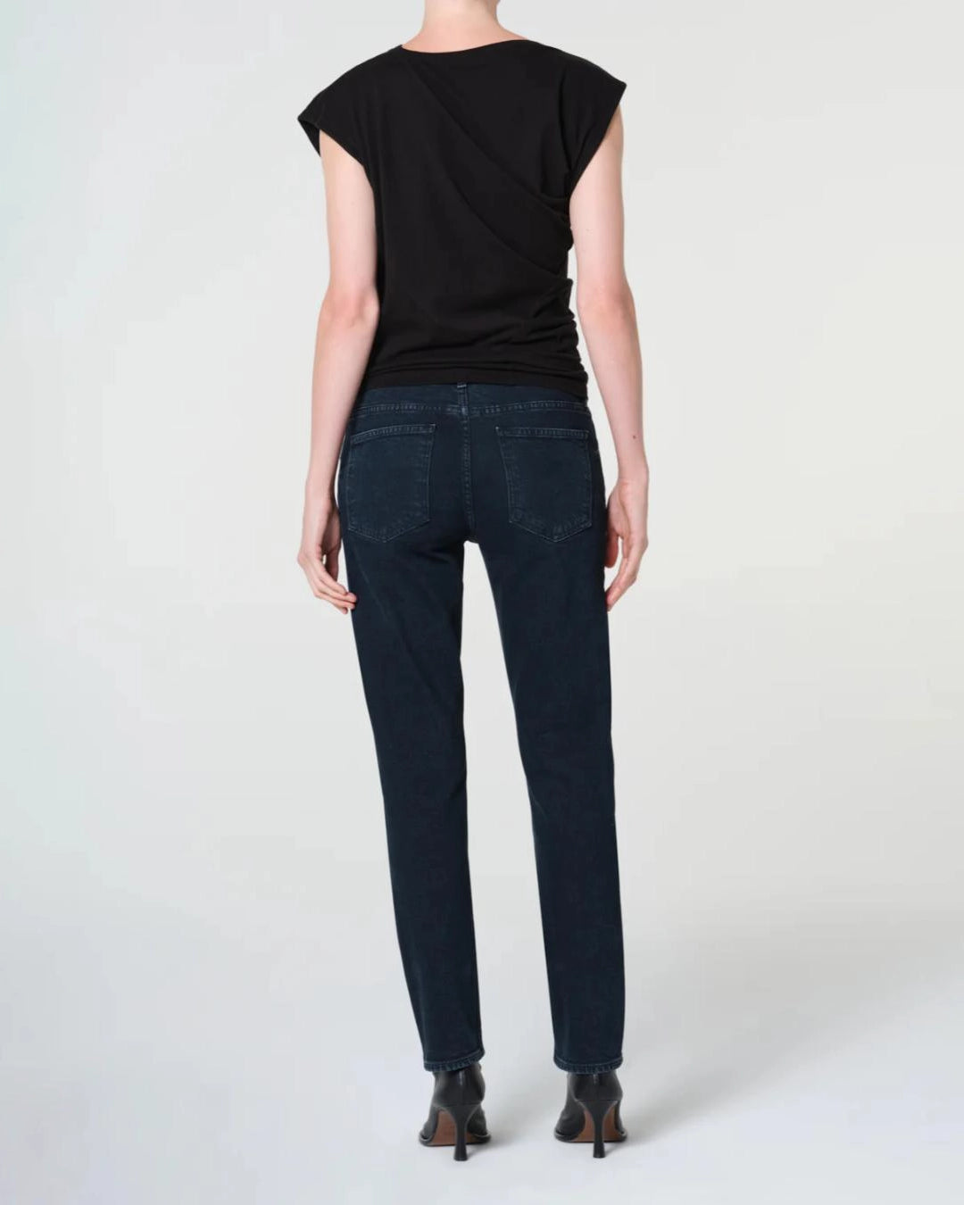 a woman wears a pair of skinny ankle cut dark denim jeans by Agolde