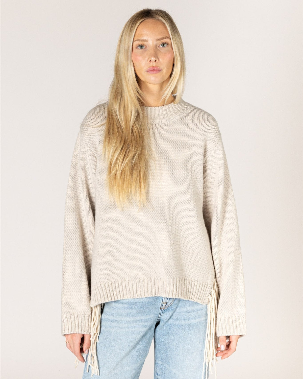 beige knit sweater with tassels on the sides