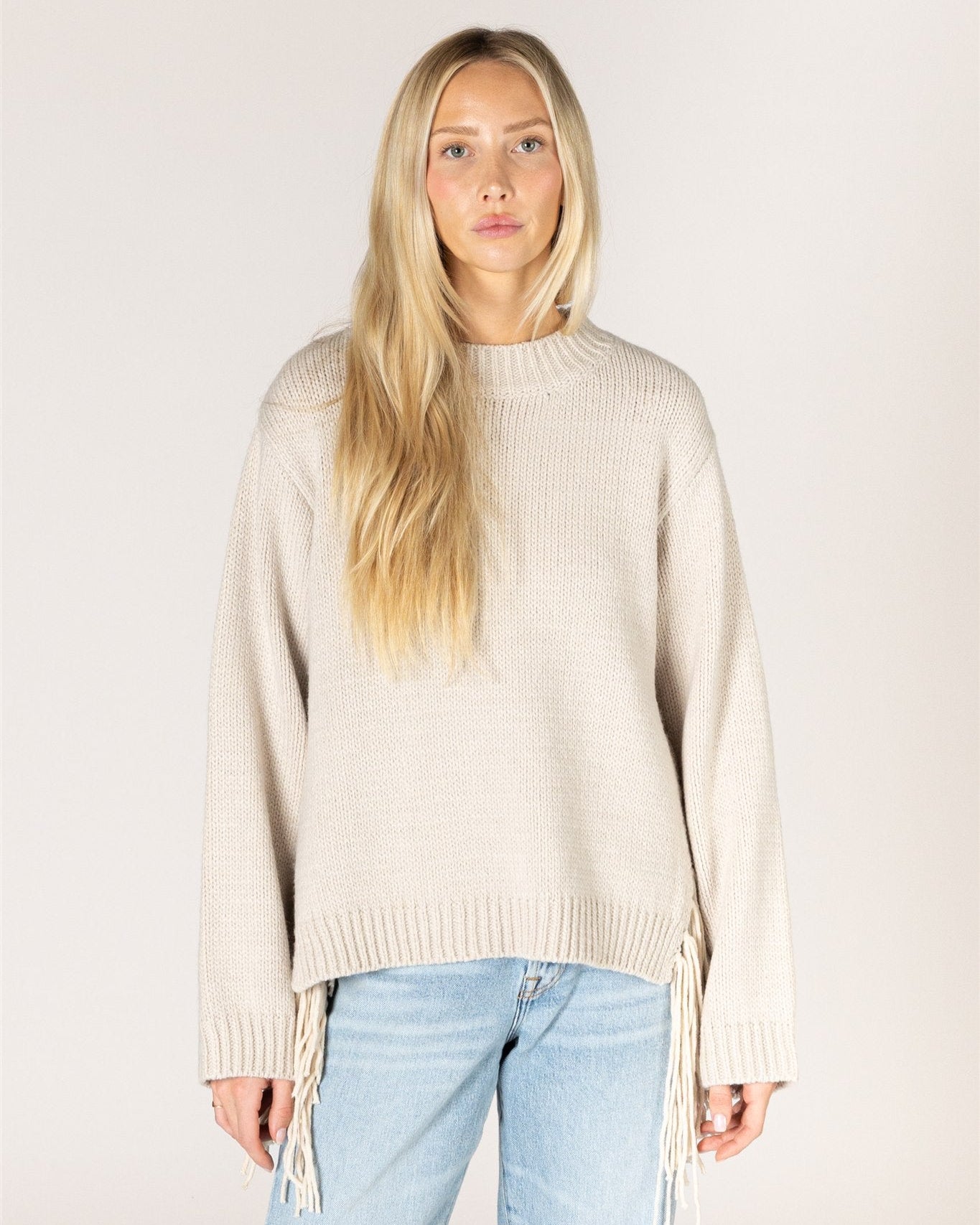 beige knit sweater with tassels on the sides
