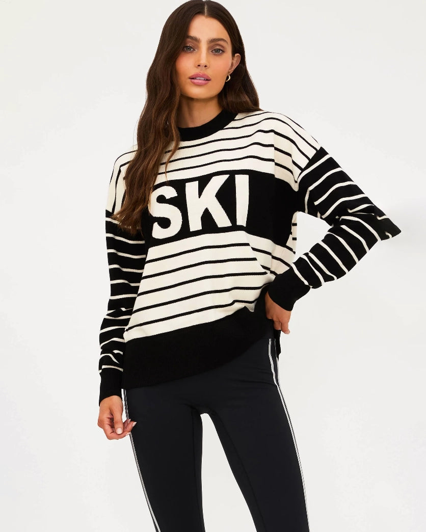 Woman wearing a black and white striped sweater with 'SKI' written on it