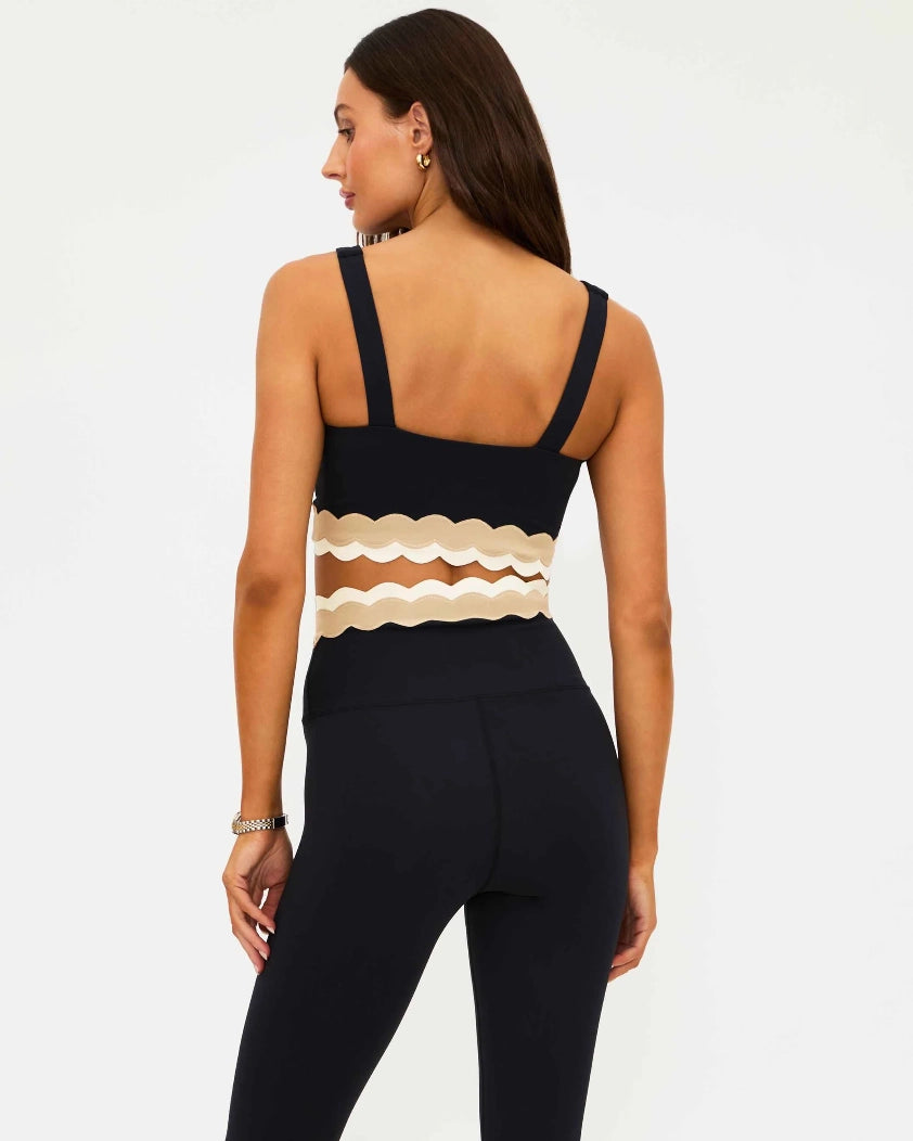 Woman wearing a black sports bra with beige ruffle detail