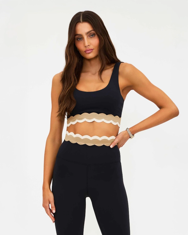 Woman wearing a black sports bra with beige ruffle detail