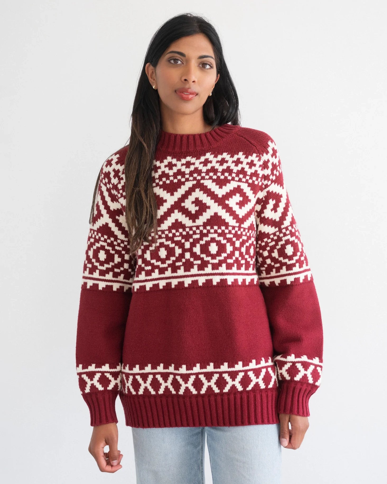 a woman wearing a fairisle sweater in burgundy with white accents