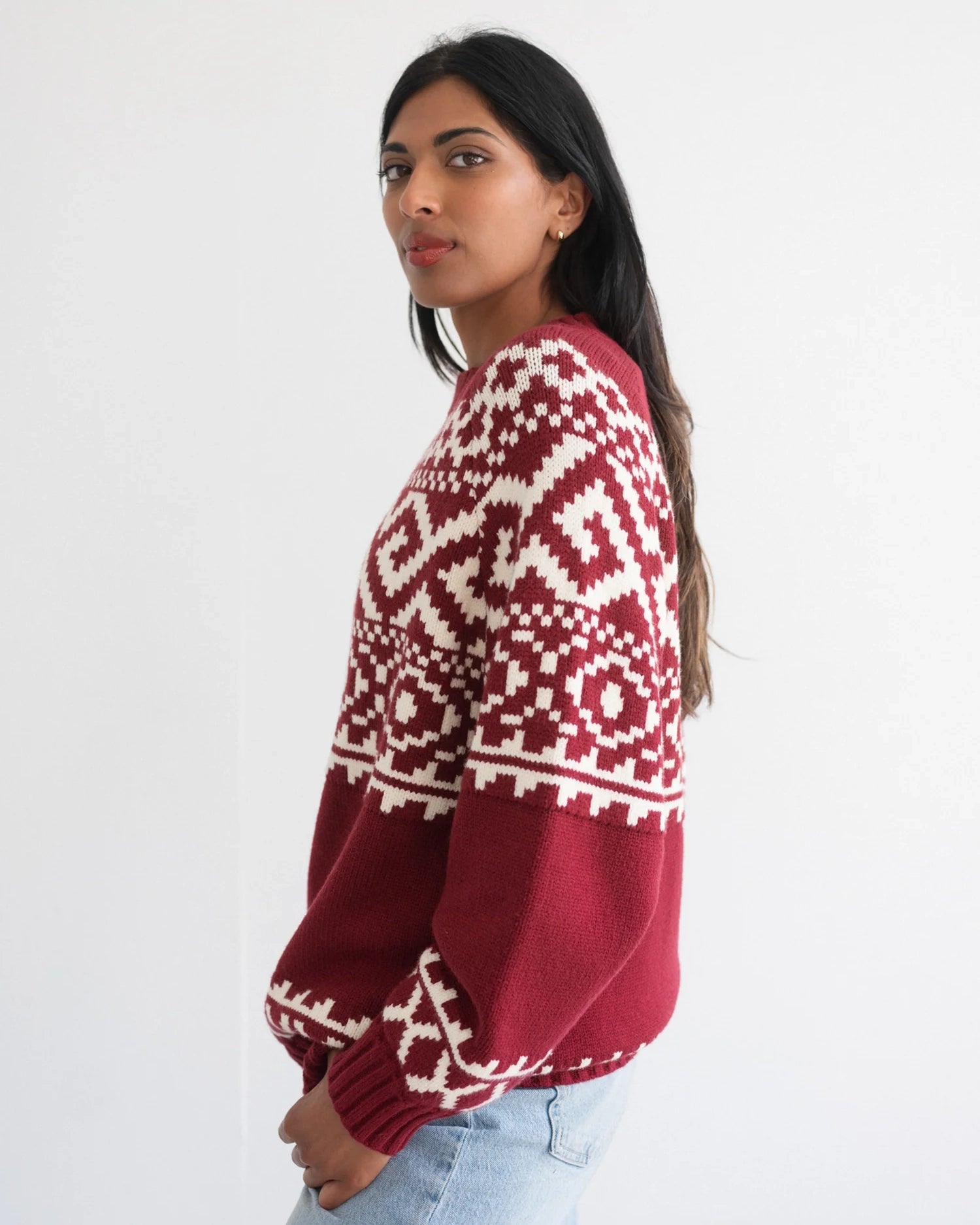 a woman wearing a fairisle sweater in burgundy with white accents