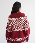 a woman wearing a fairisle sweater in burgundy with white accents