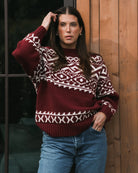 a woman wearing a fairisle sweater in burgundy with white accents