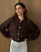 Woman wearing a brown cable knitted cardigan with large horn buttons