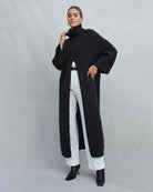 Woman wearing a long turtleneck sweater dress in black with a large slit up the front