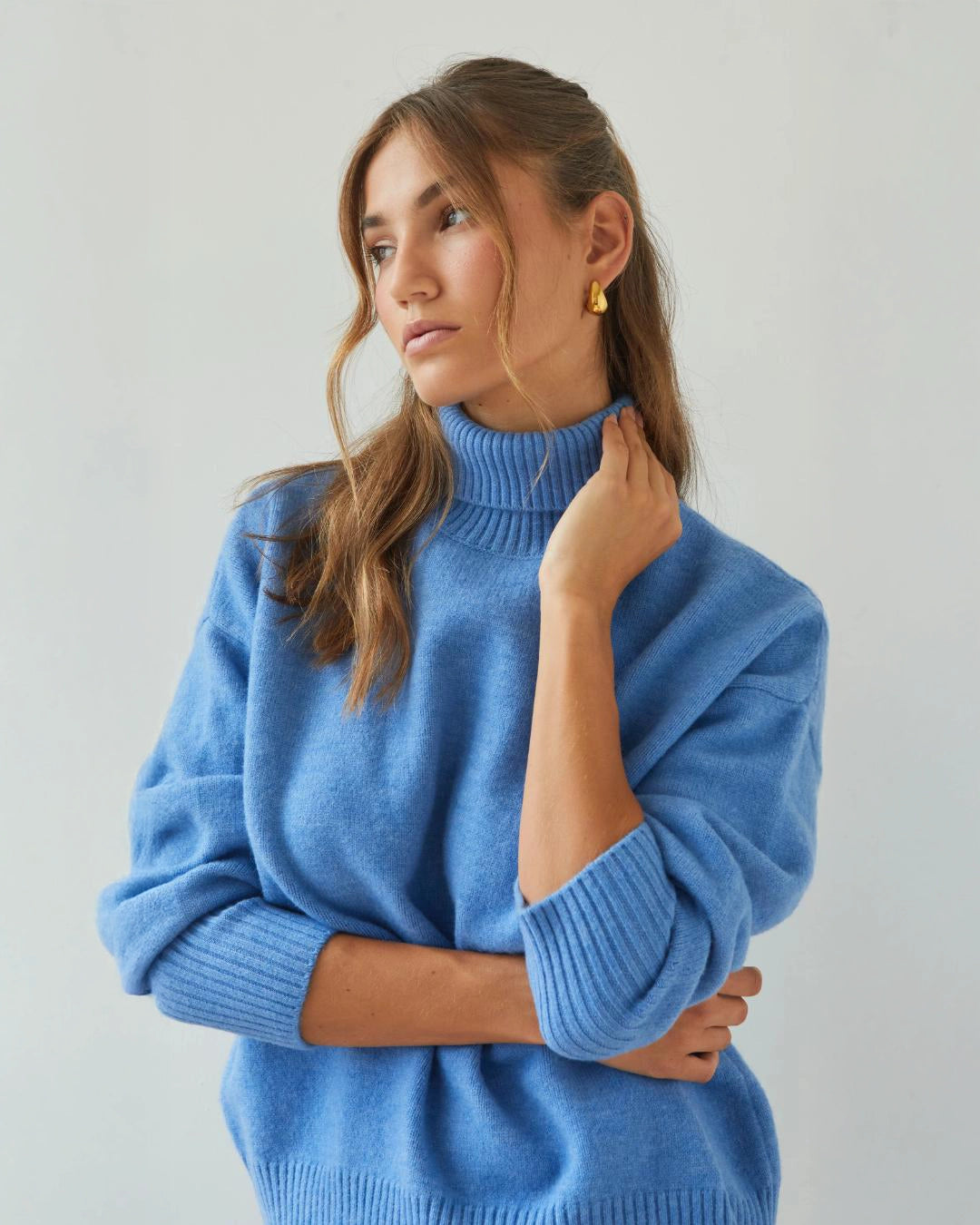 Woman wearing a relaxed fit high neck sweater in cornflower blue
