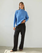 Woman wearing a relaxed fit high neck sweater in cornflower blue