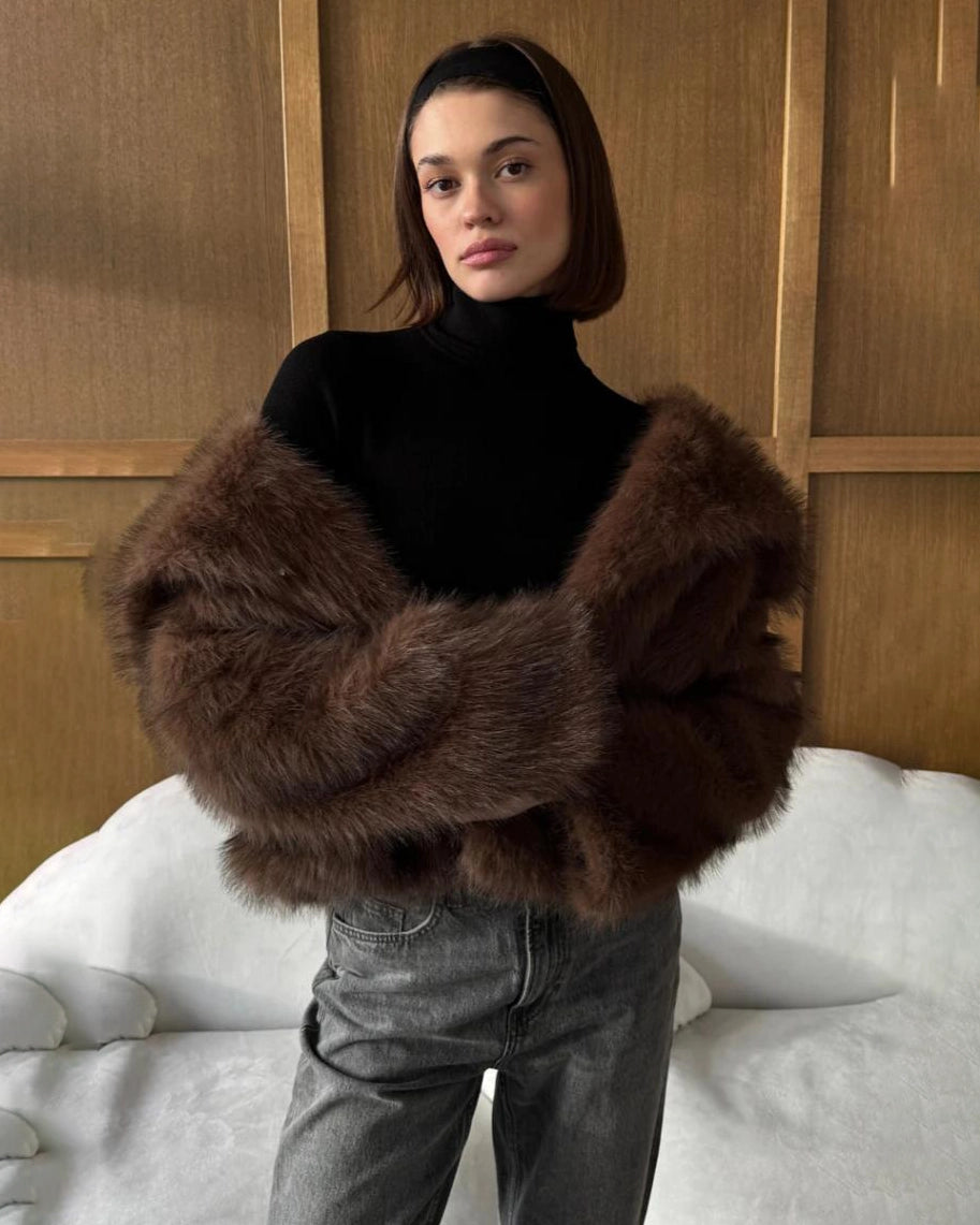 a woman wears a faux fur coat in brown with big lapels