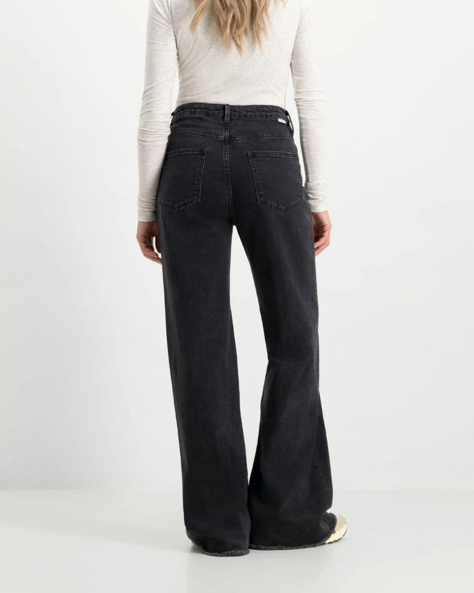 a woman wearing black flared denim jeans