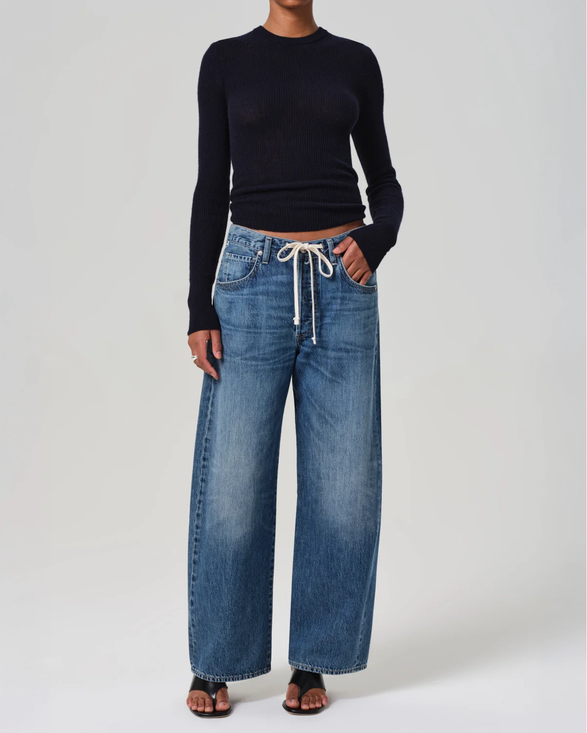 A person standing wearing wide leg blue denim jeans with a drawstring waist by Citizens of Humanity