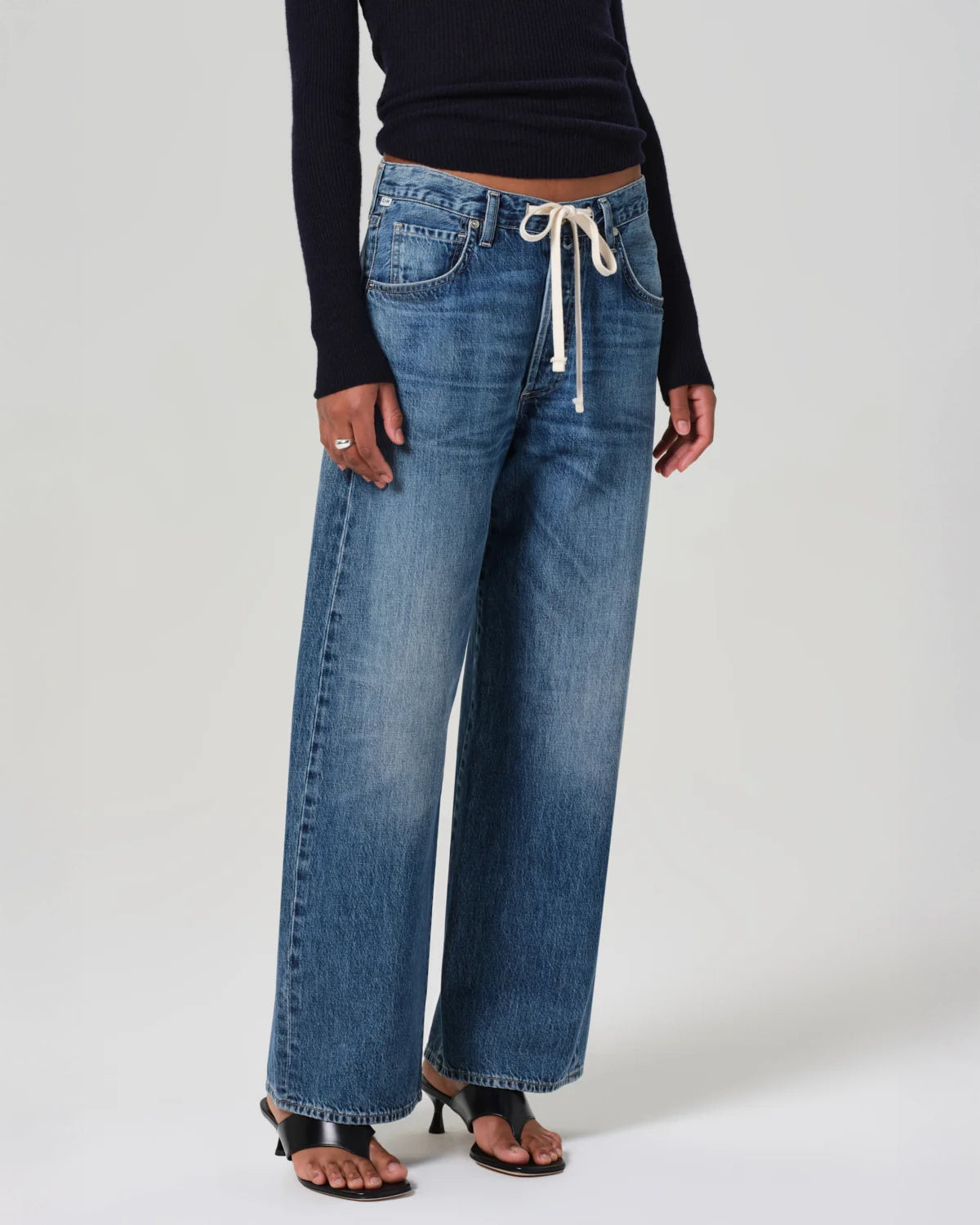 A person standing wearing wide leg blue denim jeans with a drawstring waist by Citizens of Humanity