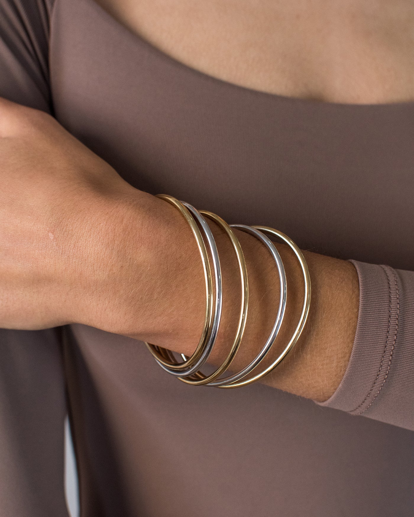 Close-up of a wrist wearing three gold and silver bangles
