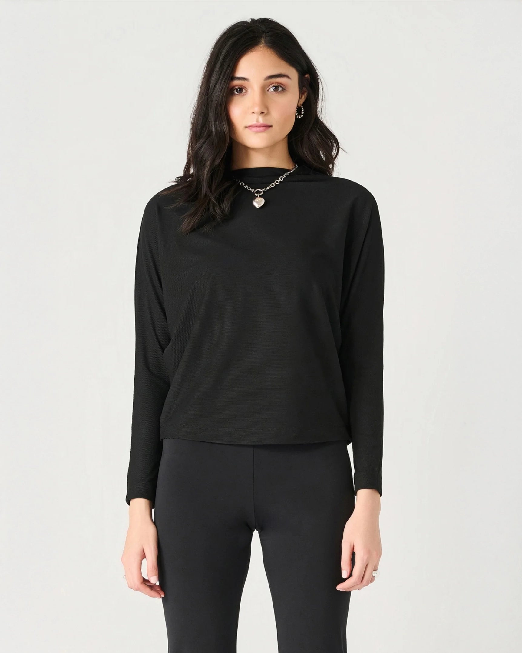 Woman wearing a ribbed mock neck top in black