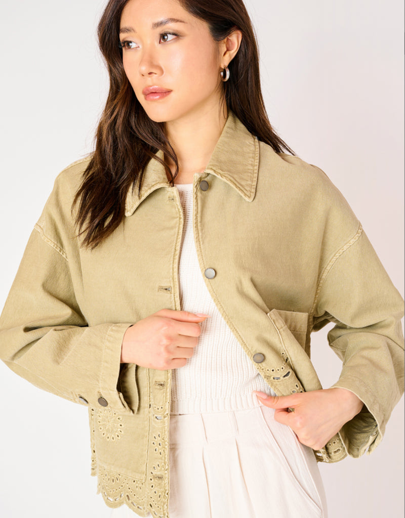 A woman wearing a khaki coloured embroidered eyelet jacket