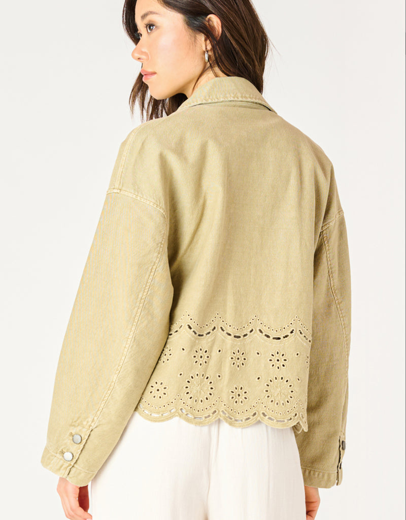 A woman wearing a khaki coloured embroidered eyelet jacket