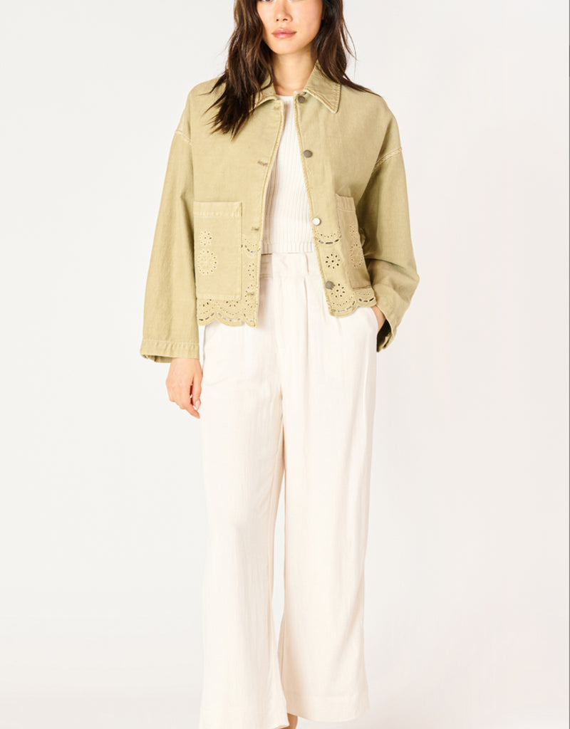 A woman wearing a khaki coloured embroidered eyelet jacket