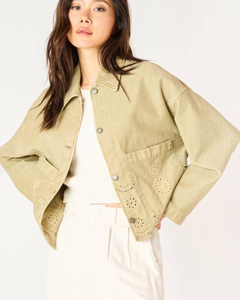 A woman wearing a khaki coloured embroidered eyelet jacket