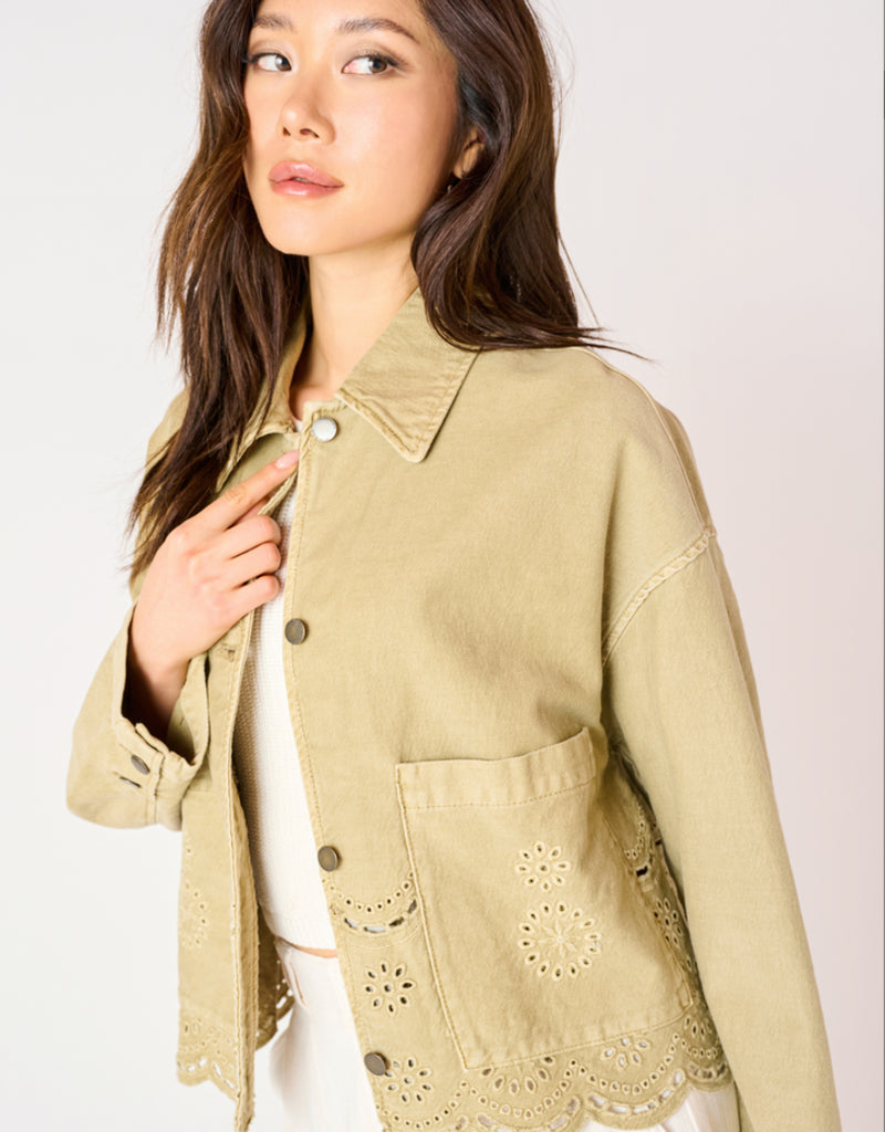 A woman wearing a khaki coloured embroidered eyelet jacket