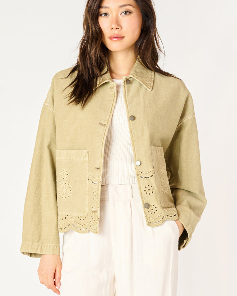 A woman wearing a khaki coloured embroidered eyelet jacket