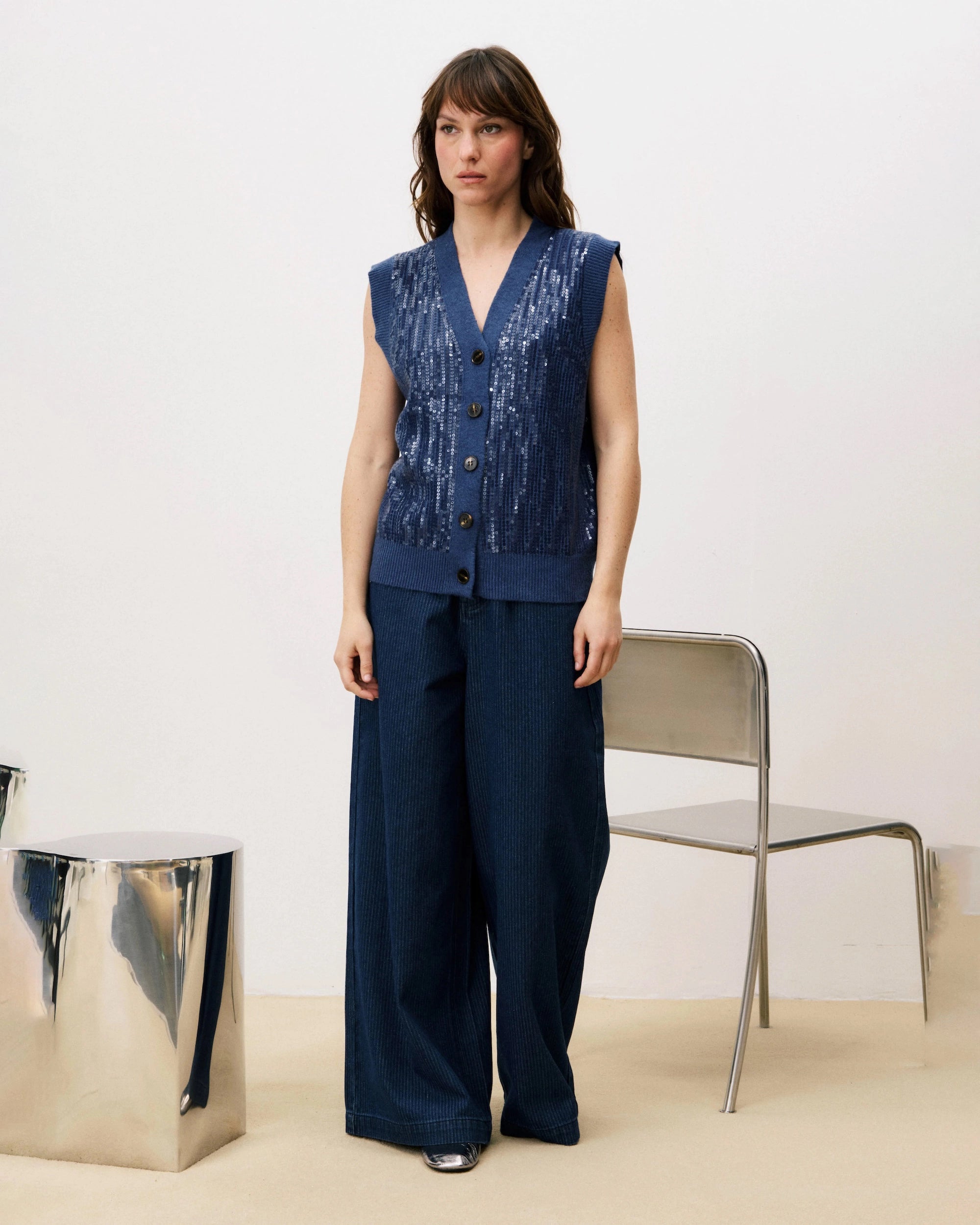Woman wearing a blue sequin knit button down vest cardigan and wide blue pants