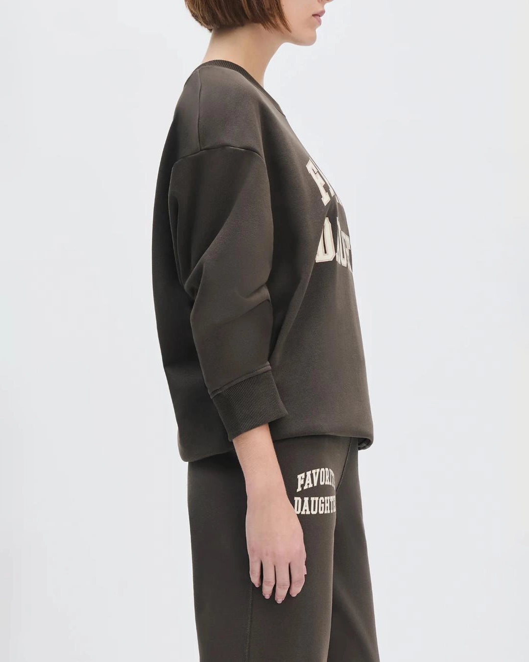 Woman wearing a sweatshirt with the words 'favourite daughter' in varsity letter on it