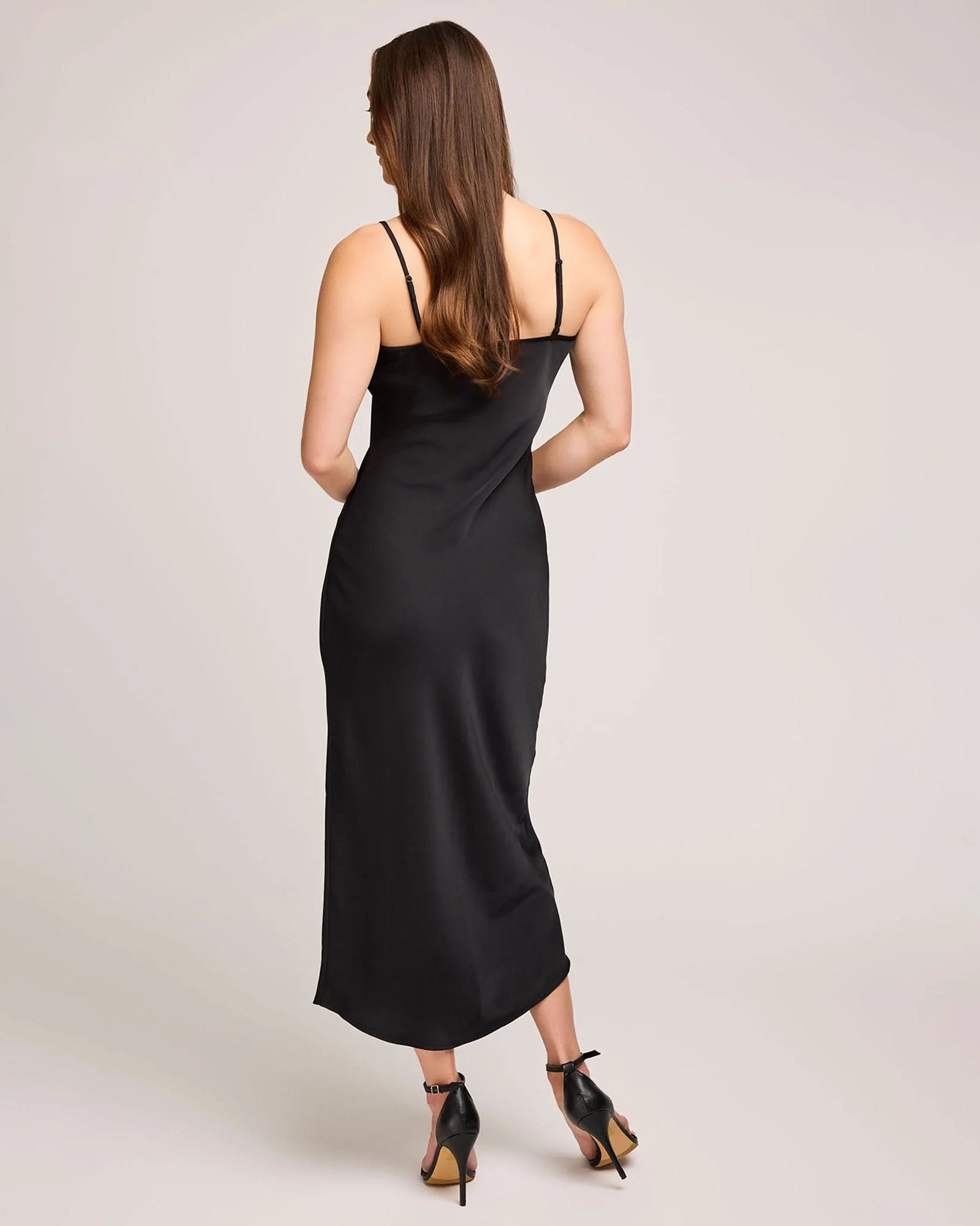 woman wearing a black satin slip dress with midi length