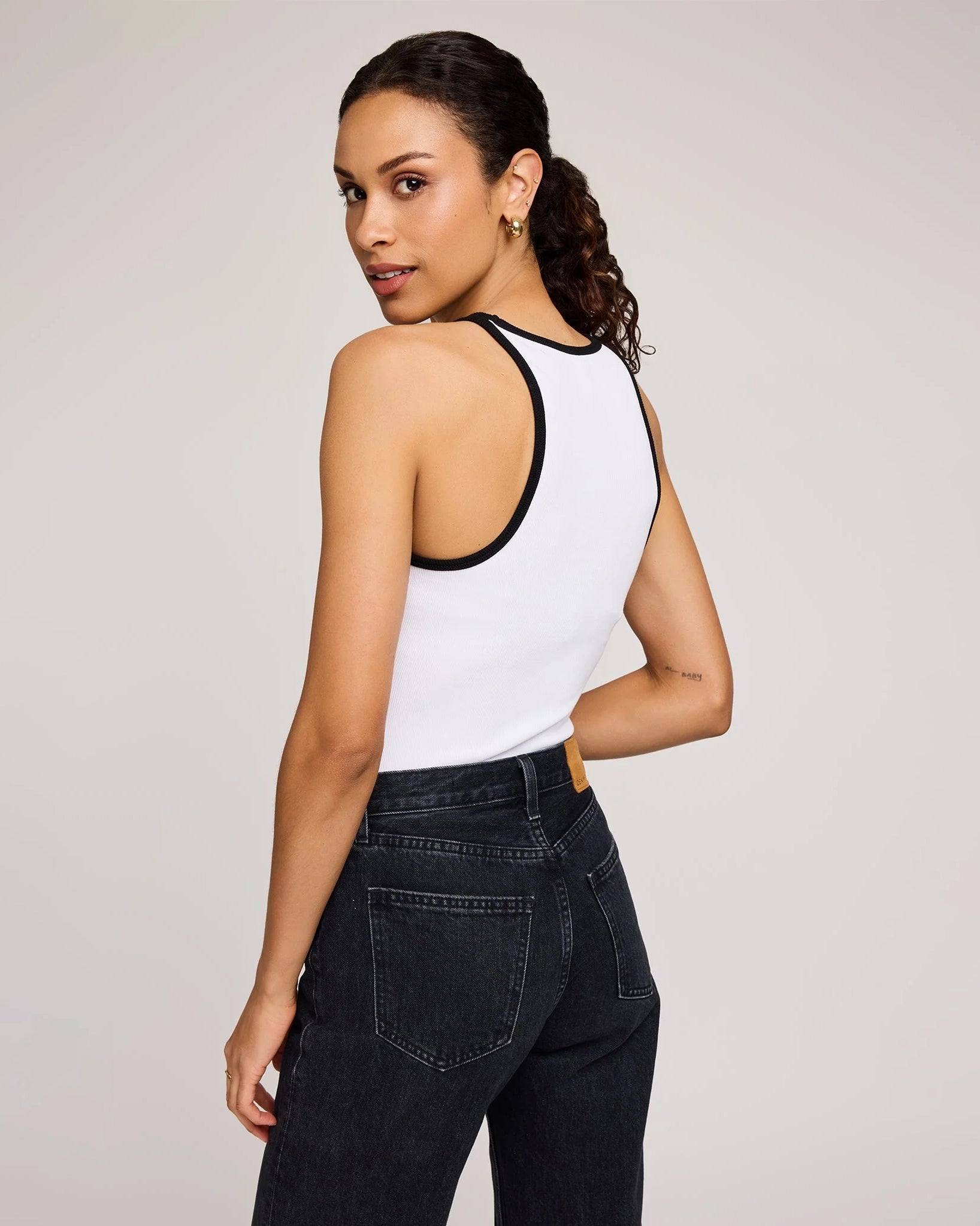 Woman wearing a white tank top with black trim