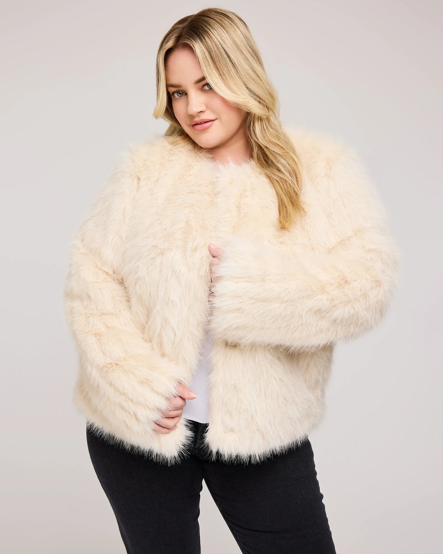 a plus sized woman wearing a faux fur jacket in cream