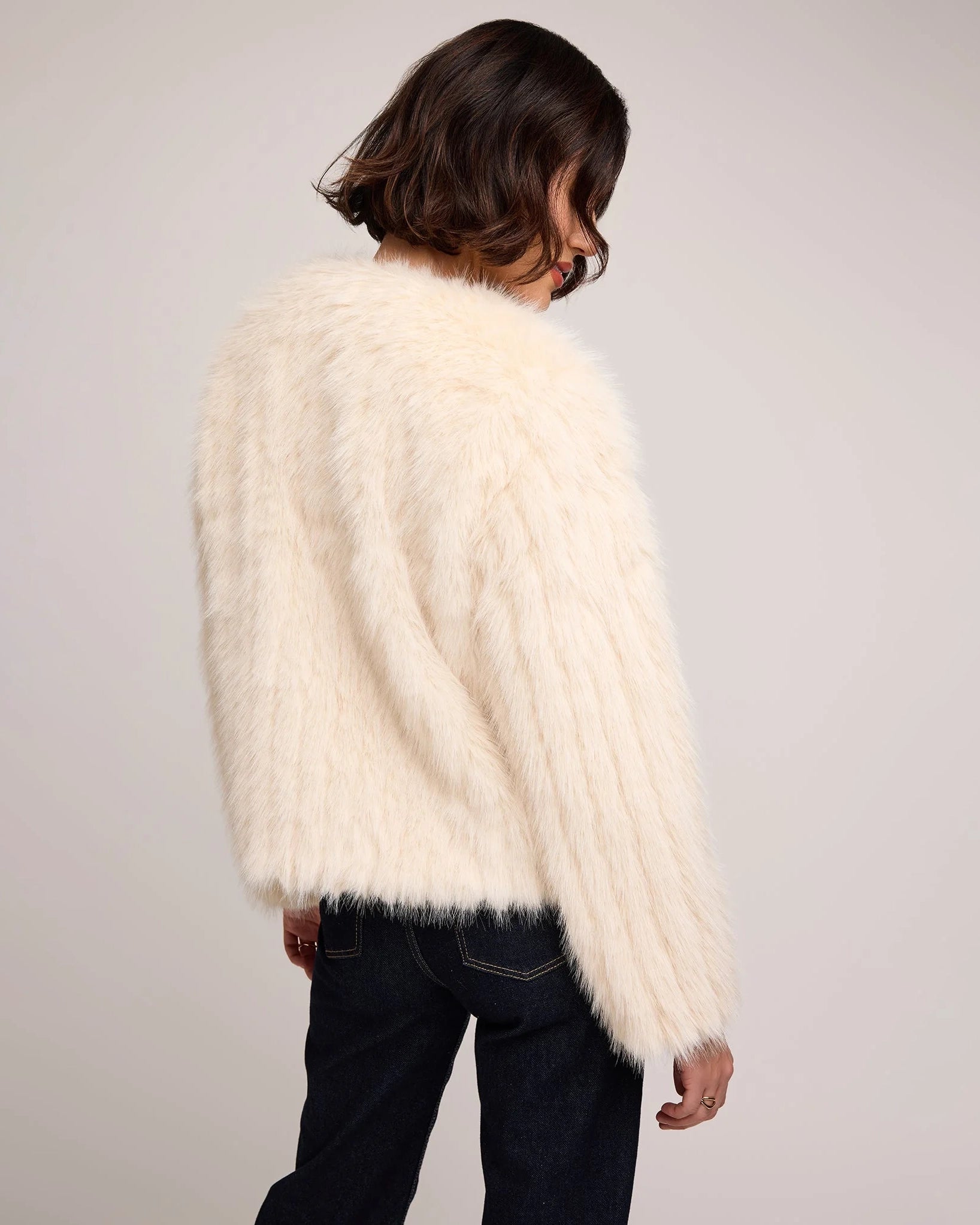 woman wearing a faux fur jacket in cream
