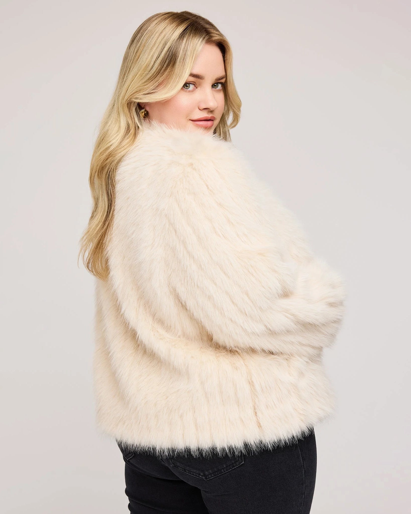 a plus sized woman wearing a faux fur jacket in cream