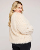 a plus sized woman wearing a faux fur jacket in cream