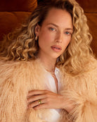 A woman wearing a gold-plated band ring with metallic gold studs and a textured surface.