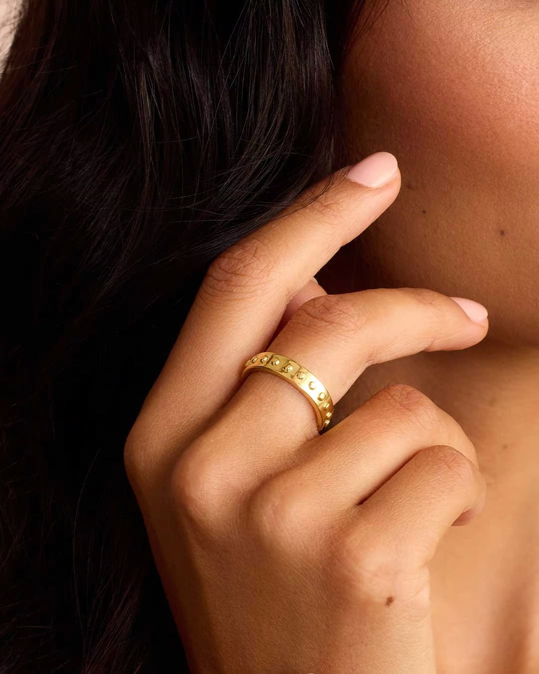 A gold-plated band ring with metallic gold studs and a textured surface.