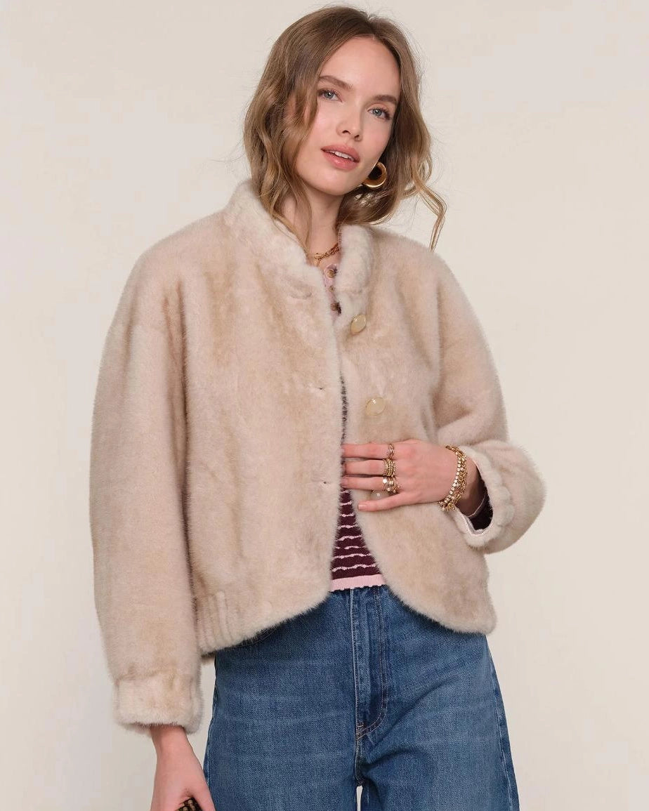 a woman wears a faux fur jacket in a light colour