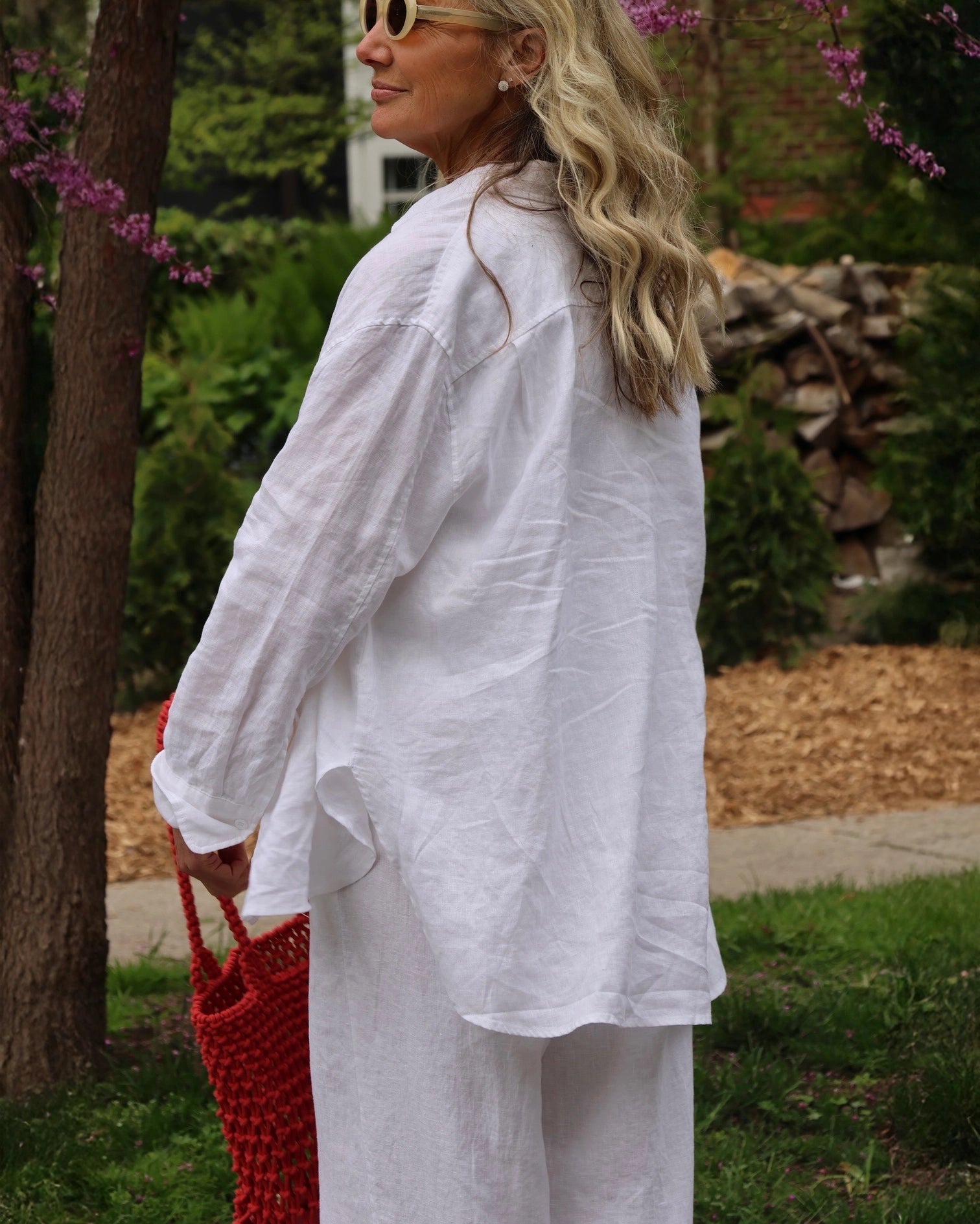 Woman in a white linen shirt and pants outdoors.