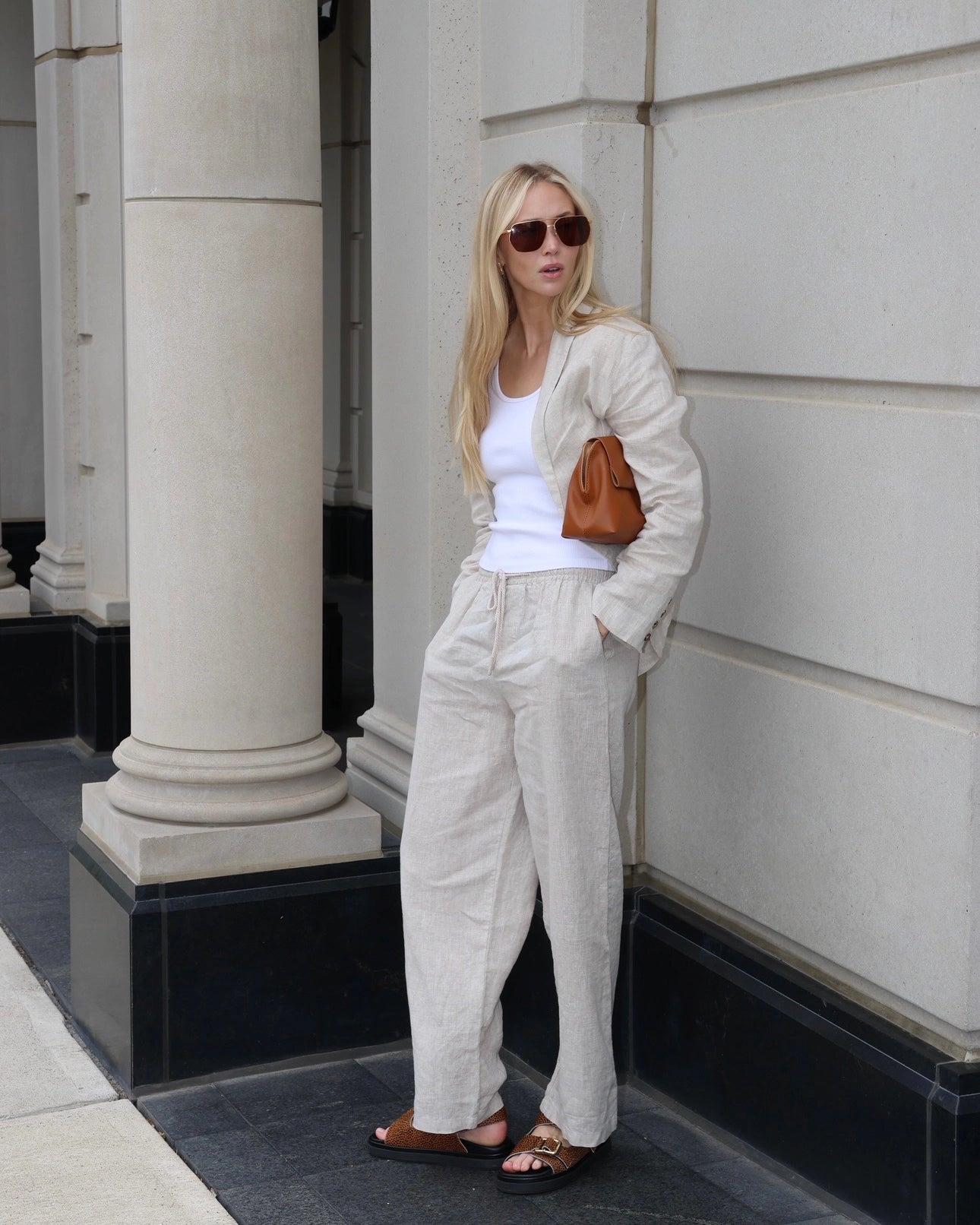 Woman wearing a beige linen blazer, white top, and linen pants