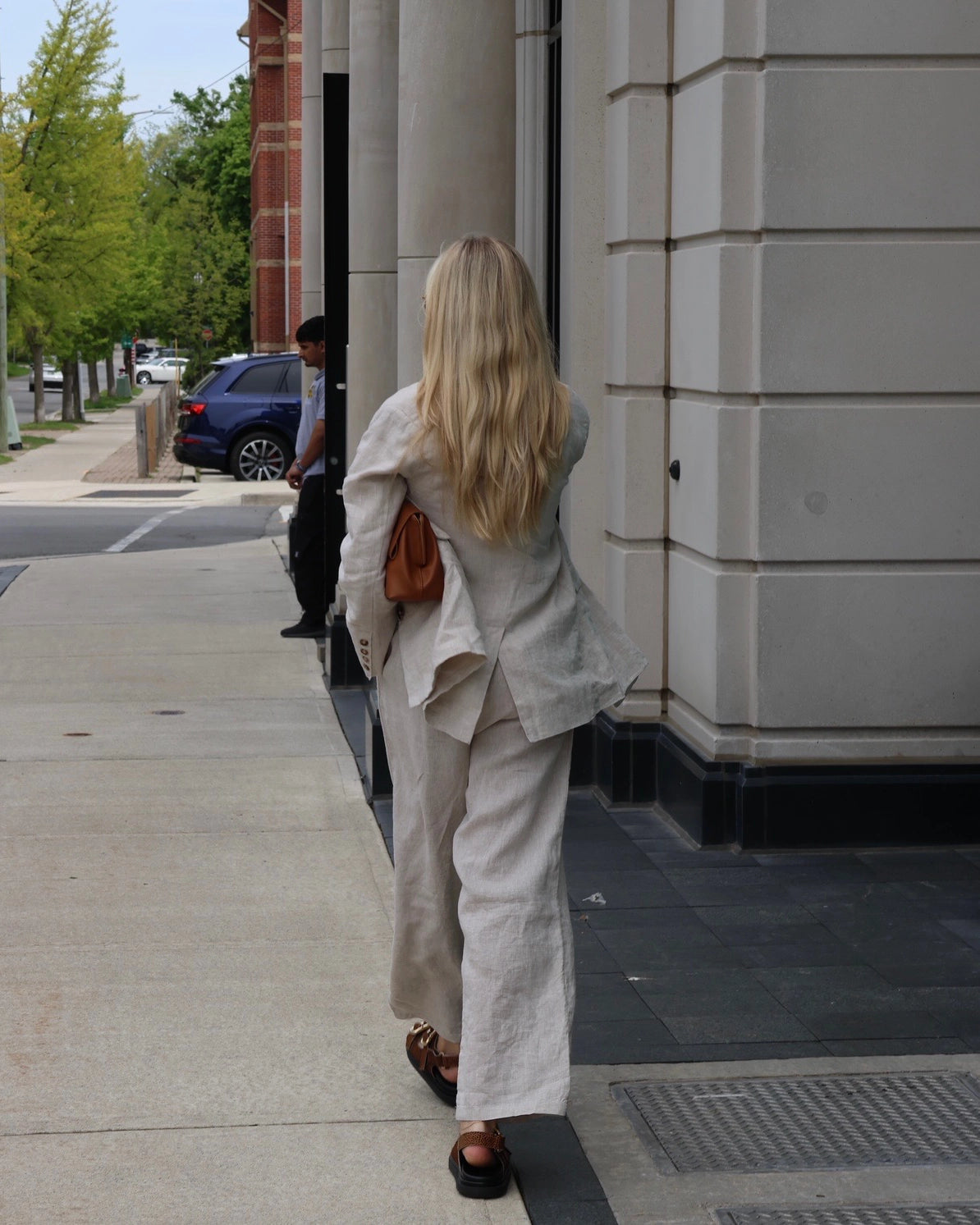 Woman wearing a beige linen blazer, white top, and linen pants