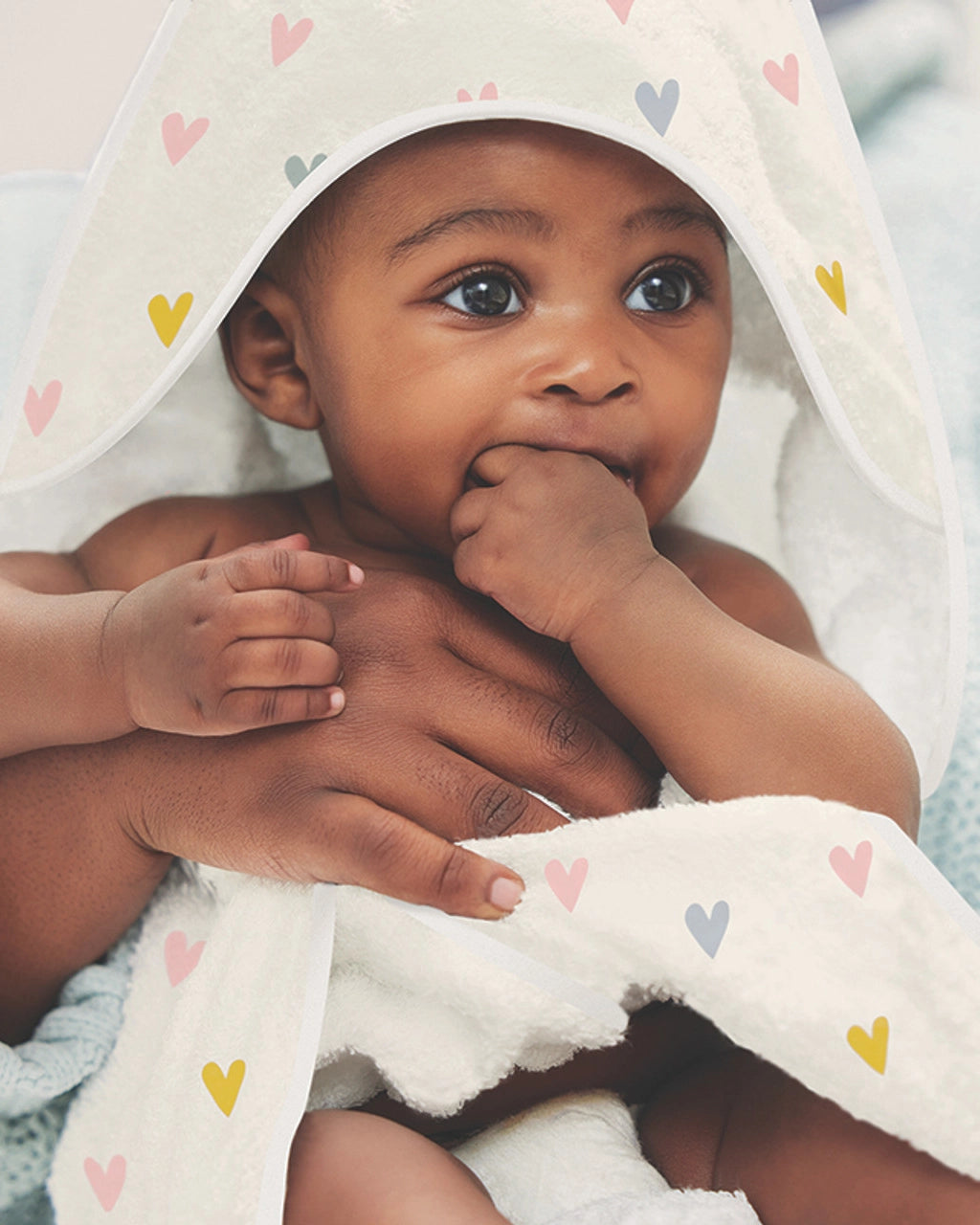 A baby wearing a hooded towel with a heart pattern on it