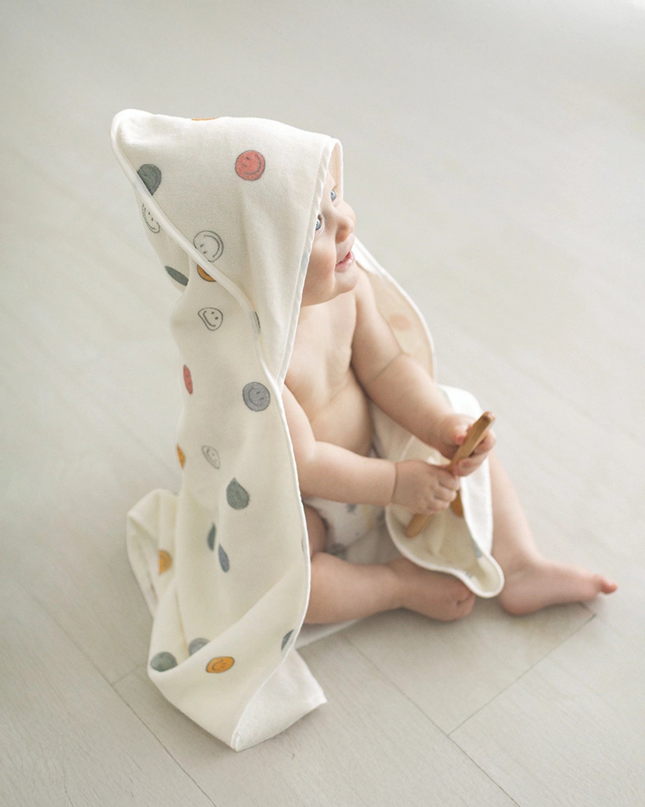 A baby wearing a hooded towel with a smiley face pattern on it