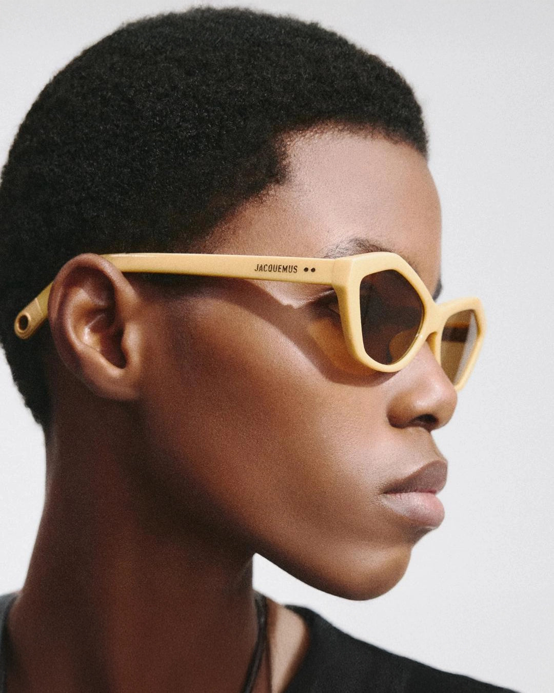 woman wearing yellow hexagonal sunglasses with brown lenses by Jacquemus