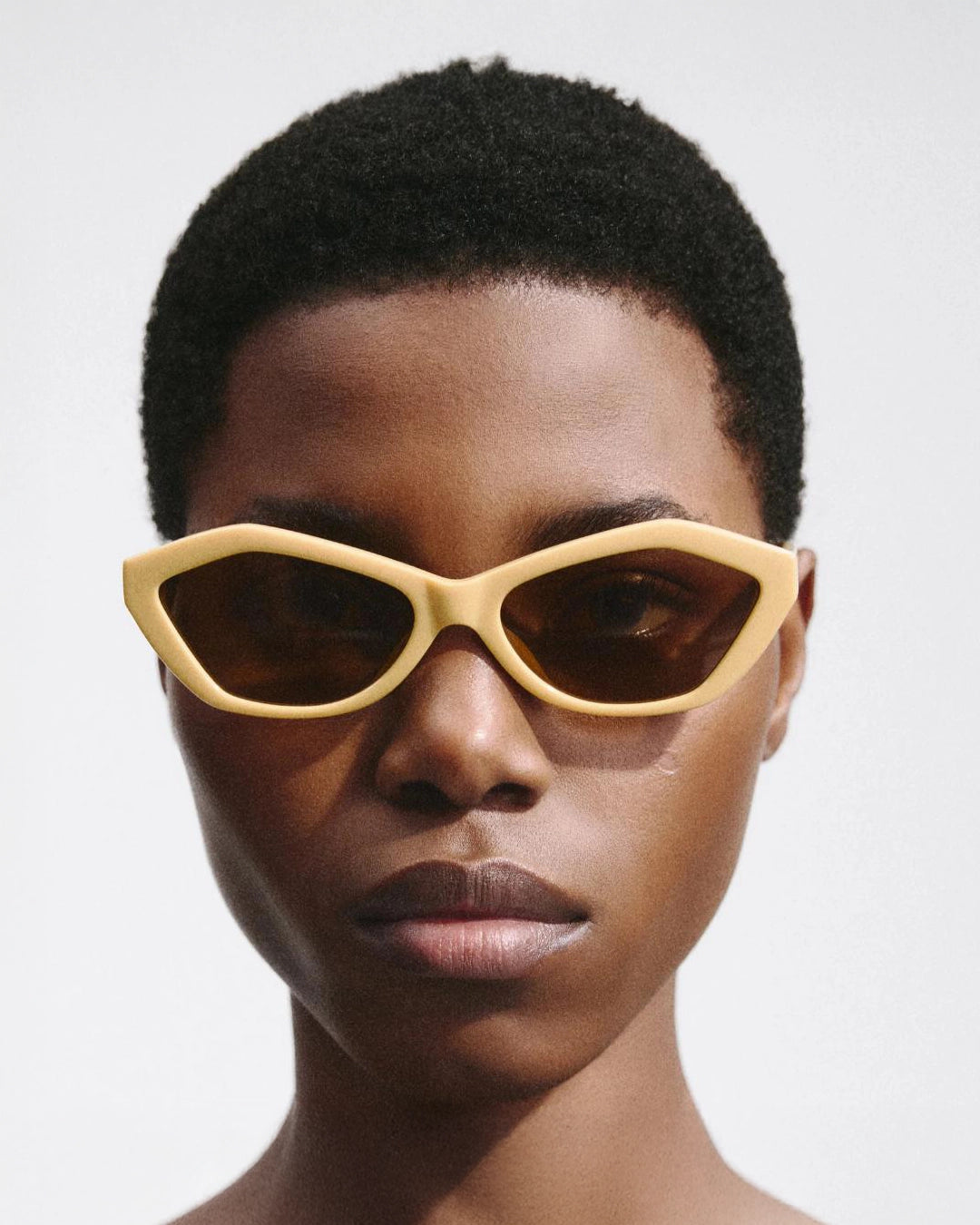 woman wearing yellow hexagonal sunglasses with brown lenses by Jacquemus